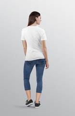 Rear view of standing beautiful female model wearing white plain crew neck t shirt in blue denim jeans capri pant. Isolated background