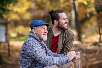 Senior father and his son on walk in nature, standing and talking.