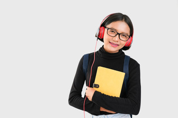 Young asia girl listen to music and hold yellow book in her arm ,back to school concept.