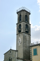 Fototapeta na wymiar Bell tower of the church of St. Jacopo and Antonio against a blue sky with clouds in Fivizzano, the small Lunigiana town in the province of Massa and Carrara, Tuscany, Italy