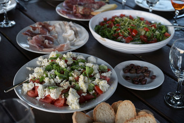 fresh mediterranean salads and antipasti meat on a rustic table for a garden dinner