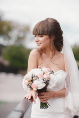 Wedding fashion bride with bouquet in hands. Young beautiful bride in an elegant dress with a bouquet at the wedding ceremony.
