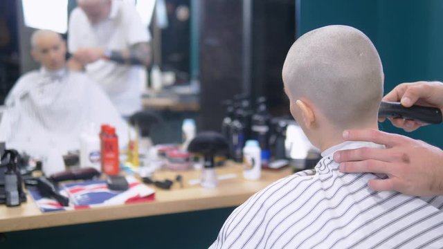 concept of hair loss after chemotherapy. the hairdresser shaves the rest of the hair on the head of a bald woman who survived after chemotherapy. hope for survival.