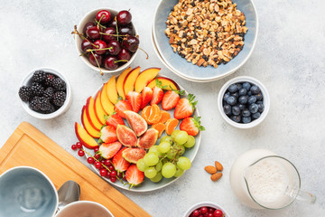 Raw vegan gluten free paleo granola or muesli made from nuts. Fruit berries platter, strawberries blueberries raspberries peach figs red currant, top view, selective focus