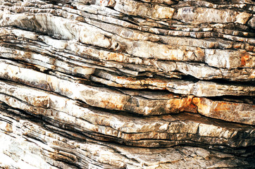 Textured layers and cracks in the rock on cliff face.