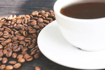 Coffe beans and white vup of coffee close up