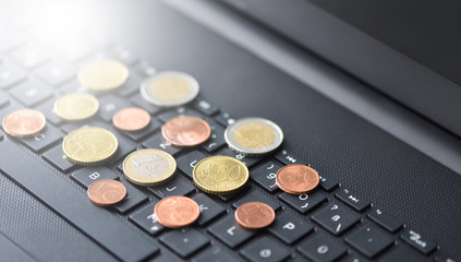 Euro coins lie on the laptop keyboard in black, close-up, symbol of working on the Internet or online payment for purchases, space for text, close-up