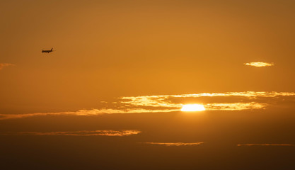 A plane flying to a holiday destination over a golden sunset