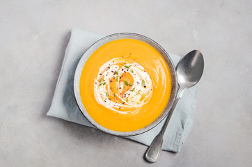 Pumpkin soup with cream and thyme on a gray concrete or stone background Top view Flat lay