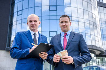 Business partners in suits making deal standing outdoors