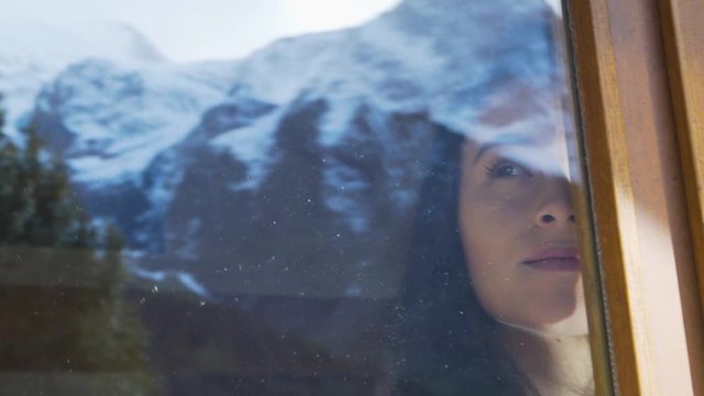 woman at a ski chalet admires mountains window in Chamonix France slowmotion