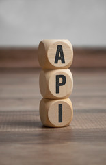 Cubes and dice with acronym API application programming interface on wooden background