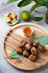 Bamboo tray with nem nuong or fried vietnamese pork meatballs on skewers, studio shot