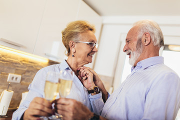 Senior couple drinking wine in home kitchen
