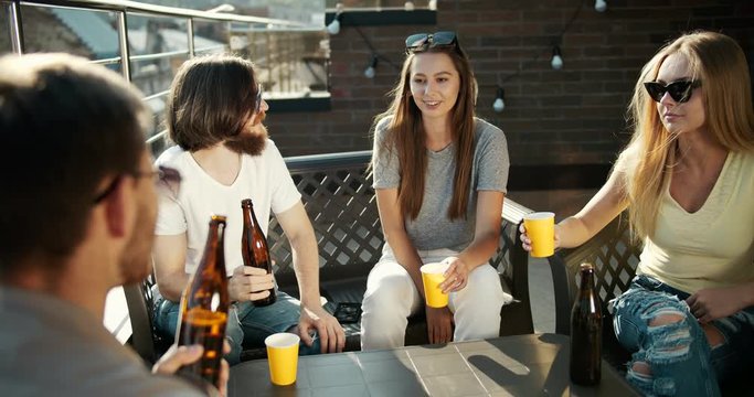 Group of fancy young cheerful friends having oof party, drinking beer, cheers