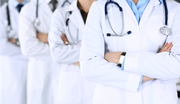 Group of modern doctors standing as a team with arms crossed in hospital office. Physicians ready to examine and help patients. Medical help, best desease treatment and medicine concept.