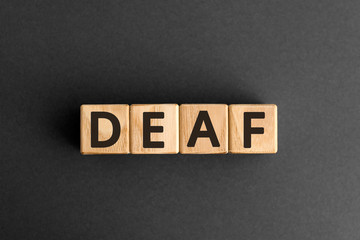 Deaf - word from wooden blocks with letters, unable to hear deaf concept,  top view on grey background