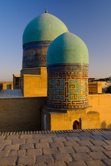Blue domes and tiled pavement of old ancient Moslem mausoleum in Samarkand in sunset light