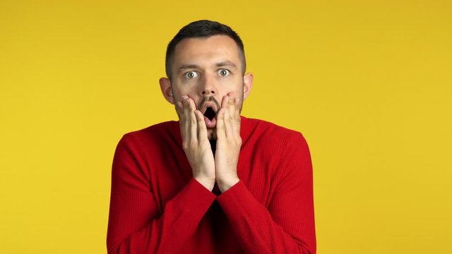 Shocked amazing man looking to camera on yellow background