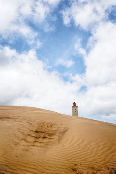 Lighthouse rising up behind a sand dune