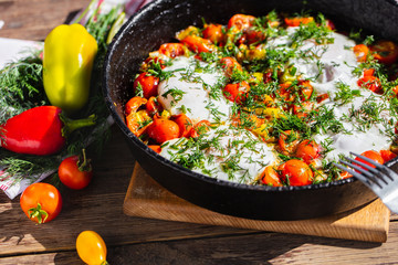 fried eggs with vegetables in a pan