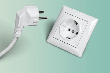 White electrical plug in the electric socket on a wall