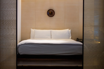 Big comfortable mattress with white bed sheet behind  sliding partitions in warm lighting room