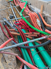 road work construction with many colorful tubes and pipes running through an unconvered ditch
