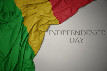 waving colorful national flag of mali on a gray background with text independence day.