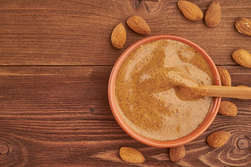 almond butter, raw food paste made from grinding almonds into a nut butter, crunchy and stir, dark brown wooden table, copy space, top view
