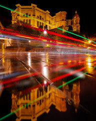 Light trails reflecting on the ground with an amazing cathedral in the background