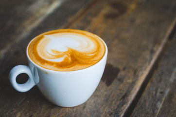 close up modern hot black coffee the cappuccino on wood background with coffee bubble foam pattern and texture in white cup looking and feel so delicious on glasses table in coffee shop.