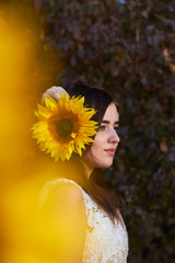 Beautiful cute sexy girl in a white dress  with deep neckline with a sunflower flower in her hair. Enjoying nature. Autumn time