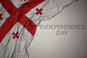 waving colorful national flag of georgia on a gray background with text independence day.