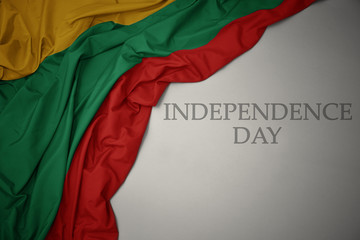 waving colorful national flag of lithuania on a gray background with text independence day.