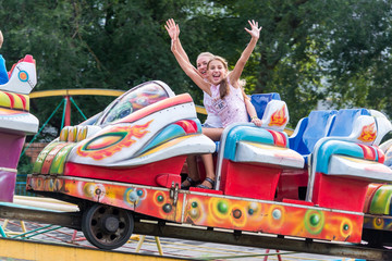 Happy mother and daughter, like sisters, riding the merry-go-round together. With the speed of...