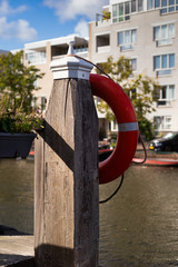 Obraz premium Orange safety belt hanging on the wooden peer near canal in Leiden, Netherlands