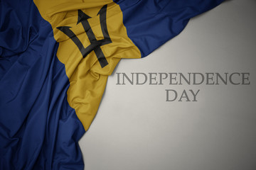 waving colorful national flag of barbados on a gray background with text independence day. - obrazy, fototapety, plakaty