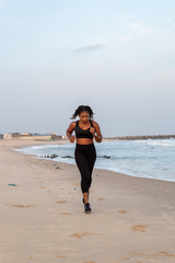 Young African lady running on the beach