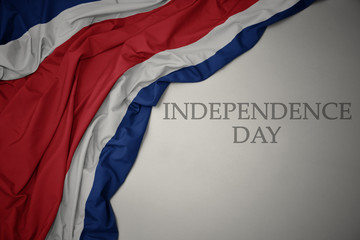 waving colorful national flag of costa rica on a gray background with text independence day. - obrazy, fototapety, plakaty