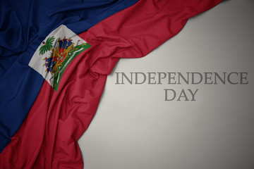 waving colorful national flag of haiti on a gray background with text independence day.