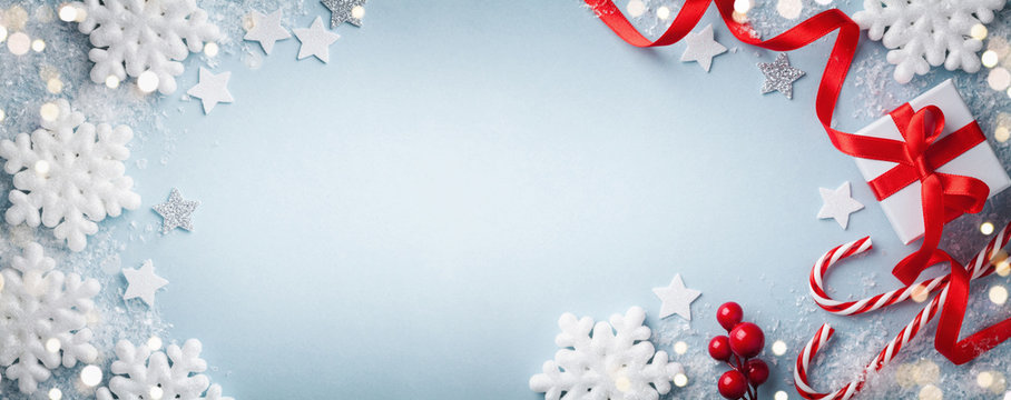 Christmas blue background. Gift or present box, white snowflakes and holiday decoration top view. Happy New Year card. Banner format.