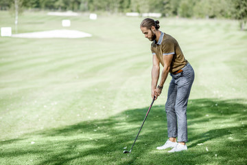 Man playing golf, swinging with putter on a beautiful course on a sunny day