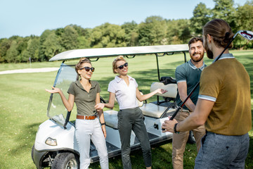 Group of a young happy friends gathering together before the golf game near the car on a playing course on a sunny day