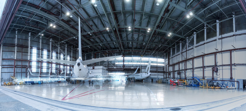 Passenger jet planes under maintenance. Checking mechanical systems for flight operations. Panorama of aircrafts in the hangar