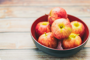 Fresh red apples In a separate bowl on wooden background.
