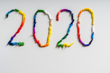 The number 2020 are painted on white canvas with bright oil paints. Top view close up.