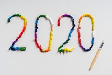 The number 2020 are painted on white canvas with bright oil paints. Top view close up.