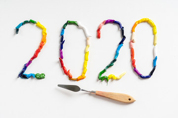 The number 2020 are painted on white canvas with bright oil paints. Top view close up.