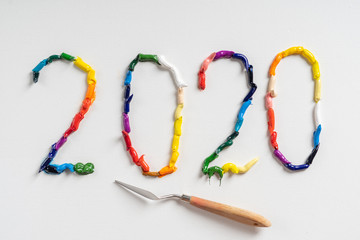 The number 2020 are painted on white canvas with bright oil paints. Top view close up.